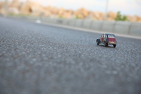 red and black die-cast vehicle scale model on asphalt road thumbnail