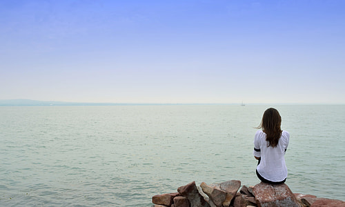 person sitting on stone in front of sea thumbnail