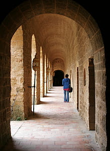 person walking on brown concrete hallway thumbnail