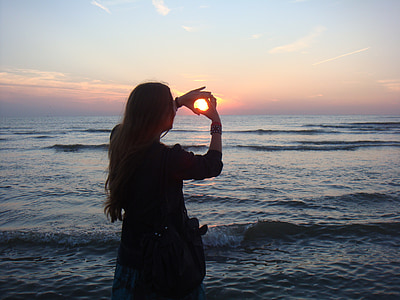 woman with black shirt hand forming hearts by the seashore thumbnail
