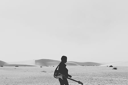 man holding guitar walking on beach thumbnail