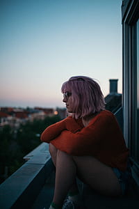 woman in red long-sleeved shirt sitting above building during sunrise thumbnail
