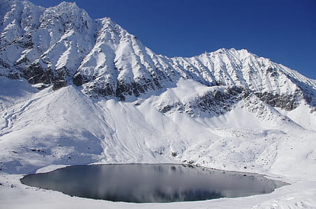 water surrounded by mountain under blue sky thumbnail