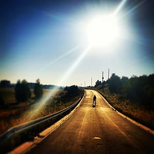 Person Standing on Blacktop Road Under Blue Sky During Daytime thumbnail