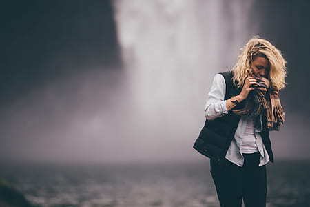 woman wearing black vest and white dress shirt near waterfalls shallow focus photography during daytime thumbnail