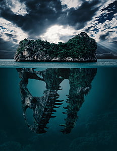 green leaf trees with dinosaur skull island on body of water thumbnail