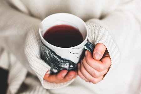 person holding beverage filled white and black ceramic mug thumbnail