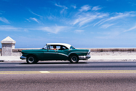 person driving classic car on concrete road thumbnail