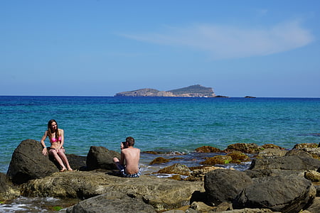 man and woman taking photo on rock shore near body of water thumbnail