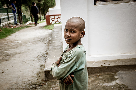 boy standing beside white concrete building thumbnail