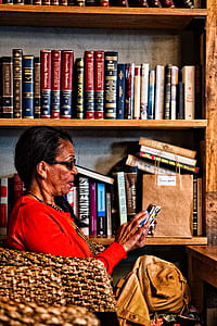 woman holding smartphone near bookshelf thumbnail