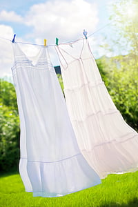 two white long dresses hanged on white rope thumbnail