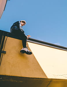 man sitting on building's rail thumbnail