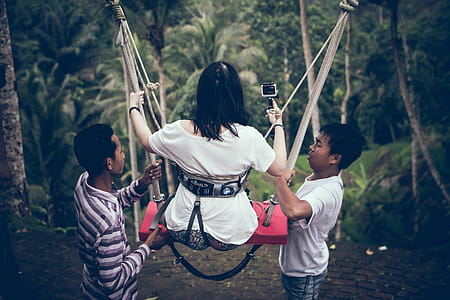 Two Men Assisting Woman Riding on Swing thumbnail