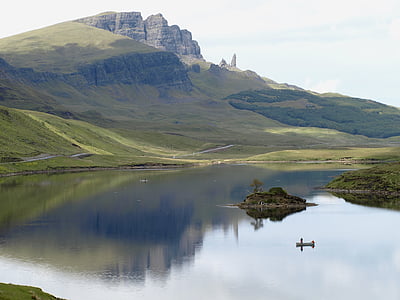 calm body of water near green mountain during daytime thumbnail