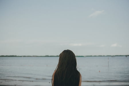 woman watching calm sea water during daytime thumbnail