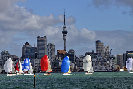 seven assorted-color sailboats on body of water near high-rise buildings during daytime thumbnail