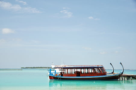 brown and blue wooden boat on body of water during daytime thumbnail