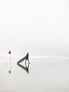 man holding long surfboard walking on shoreline thumbnail