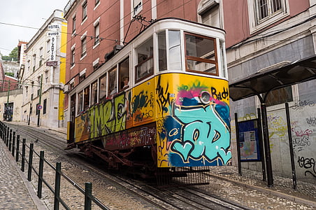 yellow and white train between buildings at daytime thumbnail