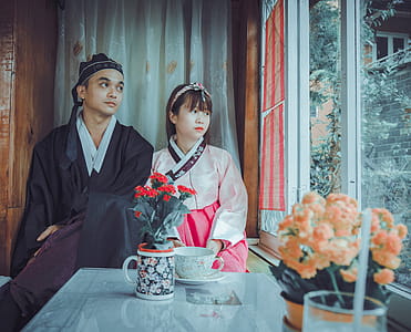 Couple Wearing Korean Traditional Dress Near Windowpane Staring at the Window thumbnail