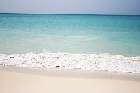landscape photography of ocean and brown seashore under clear blue sky thumbnail
