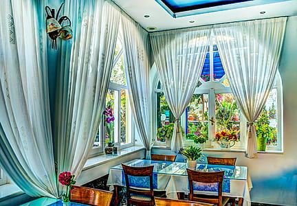 rectangular clear glass dining table with four brown wooden chairs inside room with white and green curtains thumbnail