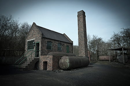 metal tank beside brown brick house thumbnail