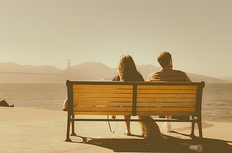 woman and man seating on brown wooden bench during daytime thumbnail