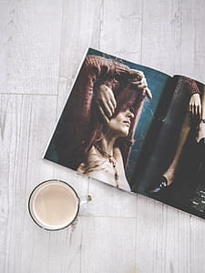 Closeup Photo of Clear Glass Cup Near Magazine on Beige Surface thumbnail
