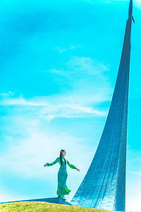 low-angle photography of standing woman standing next to gray tower during daytime thumbnail