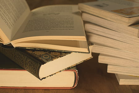 pile of assorted-title books on brown surface thumbnail