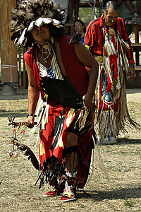 male native american holding spear standing on grass field thumbnail