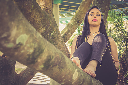 woman sitting on tree branch during daytime thumbnail