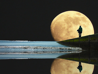 person standing at the seashore with view of full moon thumbnail