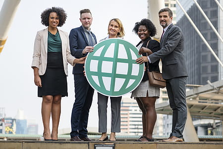 Five People Standing While Holding Green Globe Art thumbnail