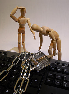 two brown wooden dolls beside computer keyboard thumbnail