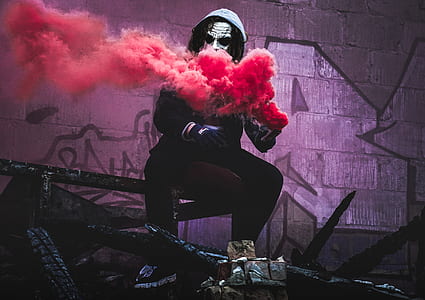 person using red smoke sitting on steel bar thumbnail