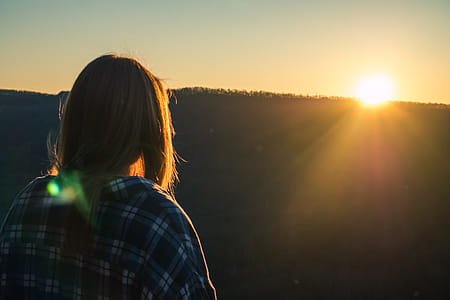 Woman Wearing Plaid Shirt Facing Sun during Golden Hour thumbnail