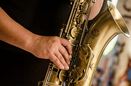 Person in Black Shirt Playing Brass-colored Saxophone thumbnail