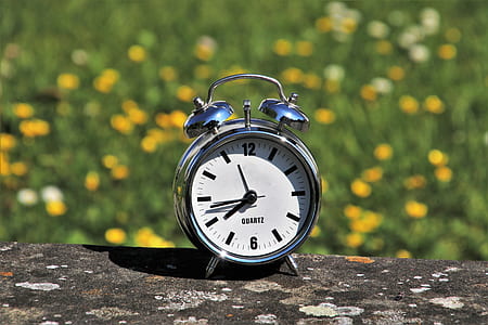 silver-colored analog alarm clock on top of brown surface thumbnail