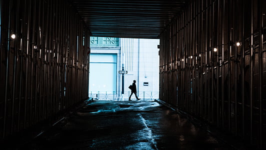 man walking beside white concrete building thumbnail