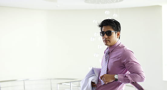 man in pink dress shirt holding white shirt thumbnail