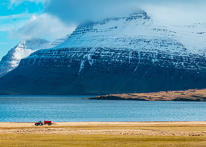snowy mountain covered by clouds beside body of water thumbnail