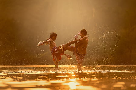 two boy playing in water during golden hour thumbnail