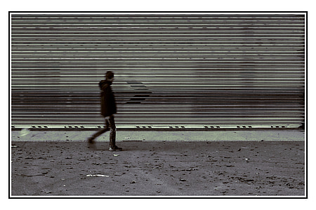 man in black hoodie walking on gray road thumbnail