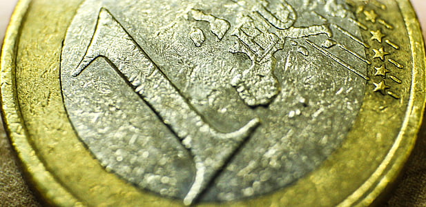 round silver-and-gold-colored 1 coin on brown surface thumbnail