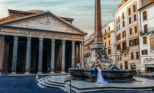 bride and groom standing near fountain and roman temple at daytime thumbnail