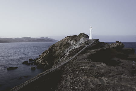 white lighthouse on mountain near shore thumbnail