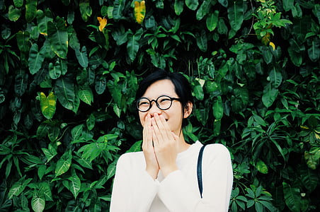 woman smiling while covering mouth beside green pkants thumbnail